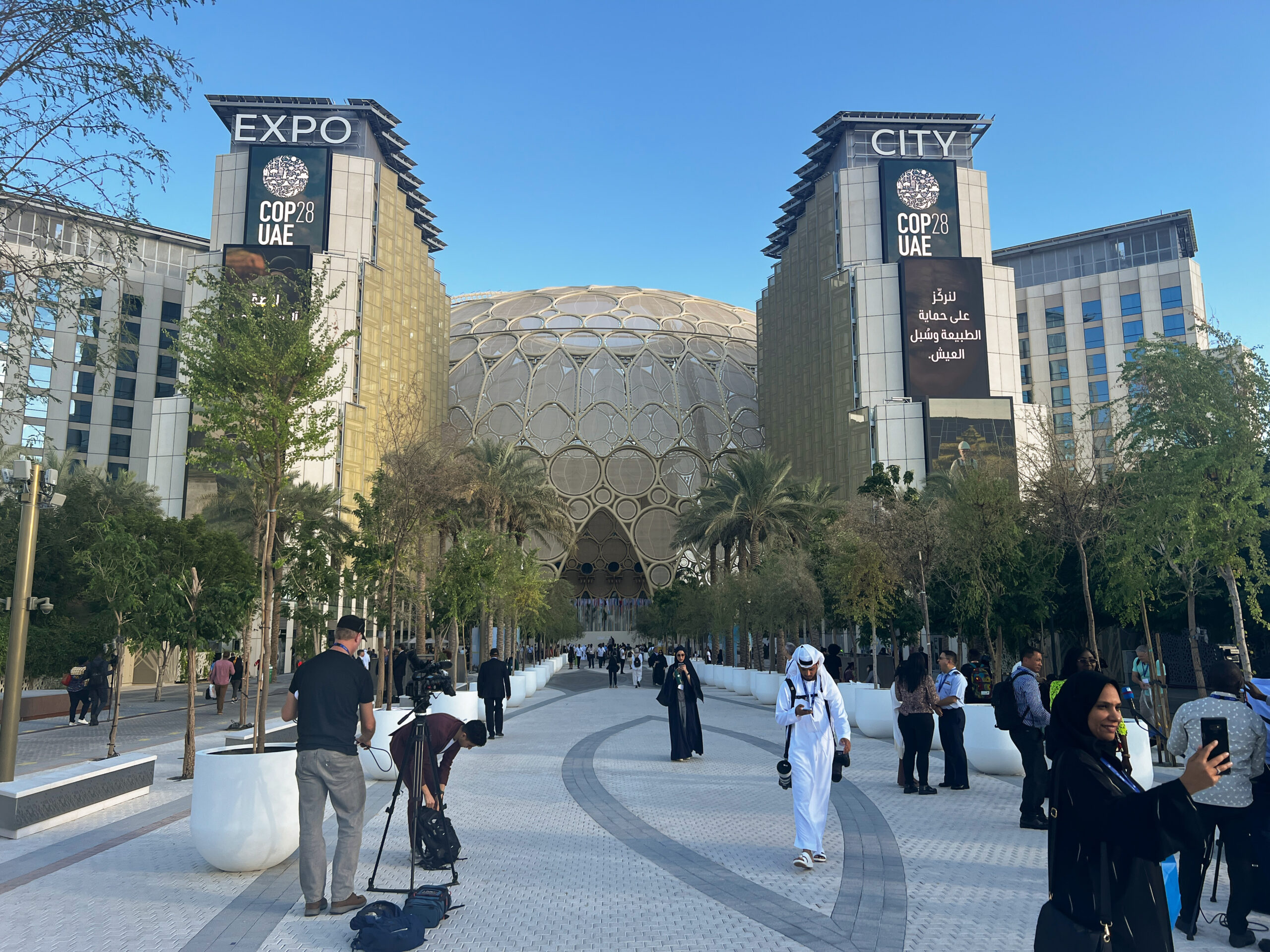 An exterior photo of a giant exhibition hall in Dubai, with posters for COP28 outside.