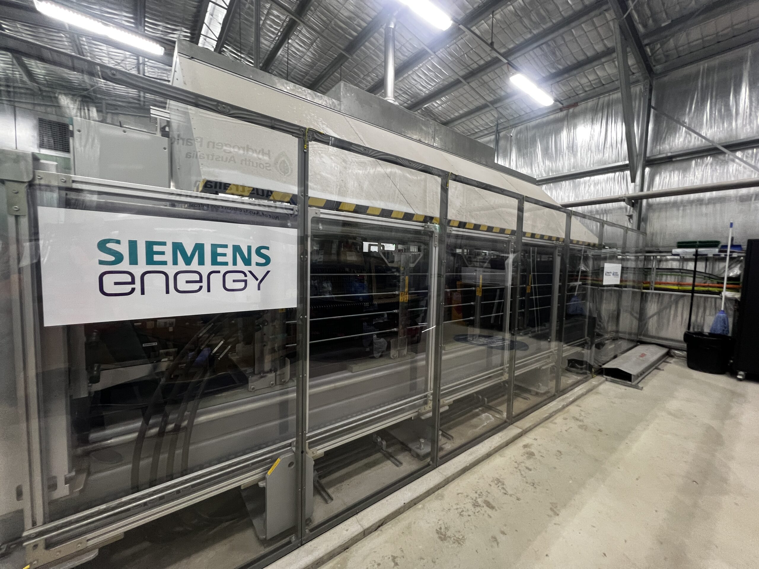 Inside a hydrogen electrolyzer facility, with a sign that says "Siemens Energy" on it. 
