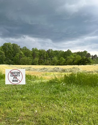 A sign opposing Piedmont Lithium's open pit mine sits on the property of Gaston County resident Warren Snowdon. IN the distance you can see the treeline where Piedmont Lithium plans to dig its mine pits. 