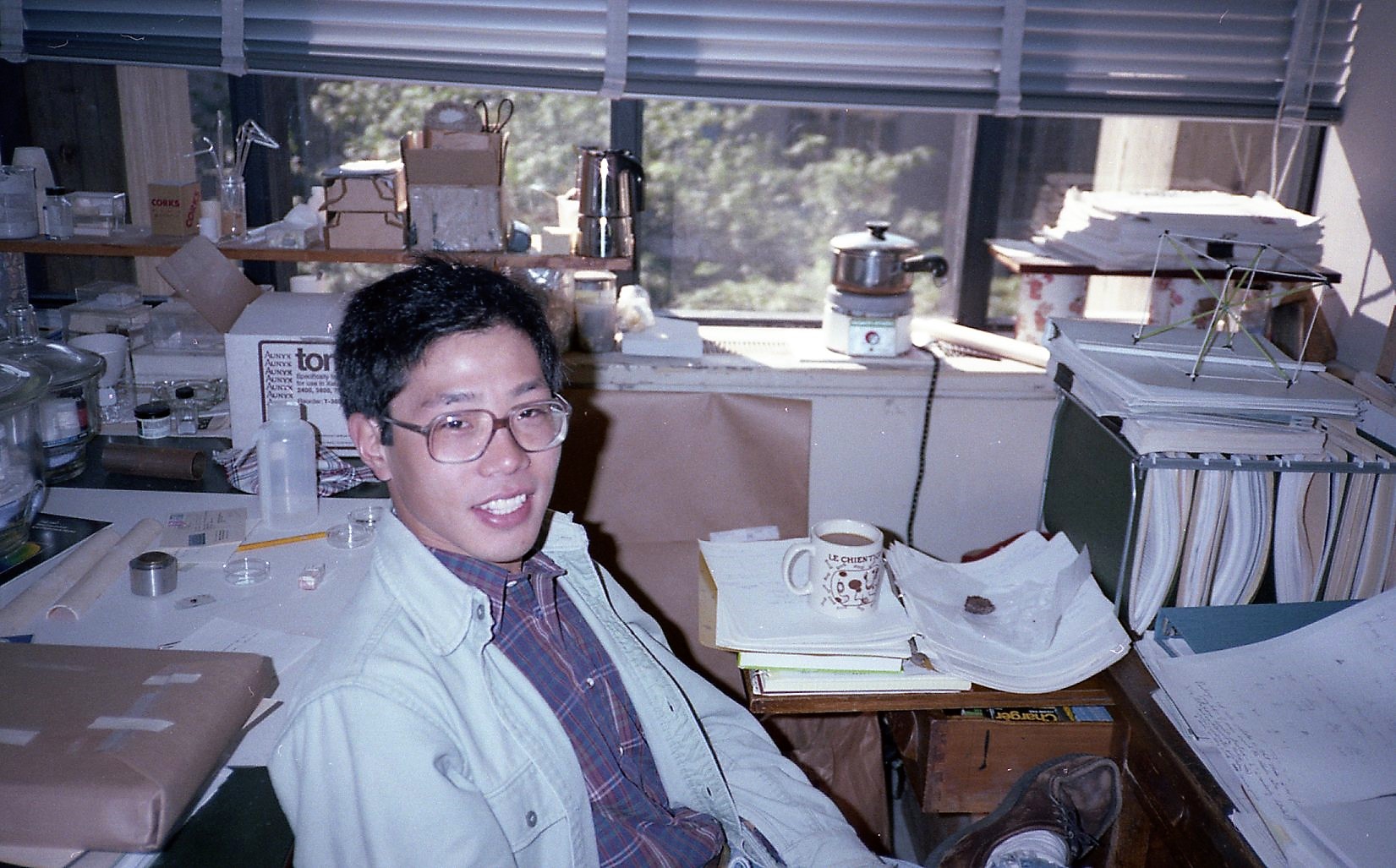 A man smiles in a scientific laboratory/office, old photograph clearly circa the 1980s.