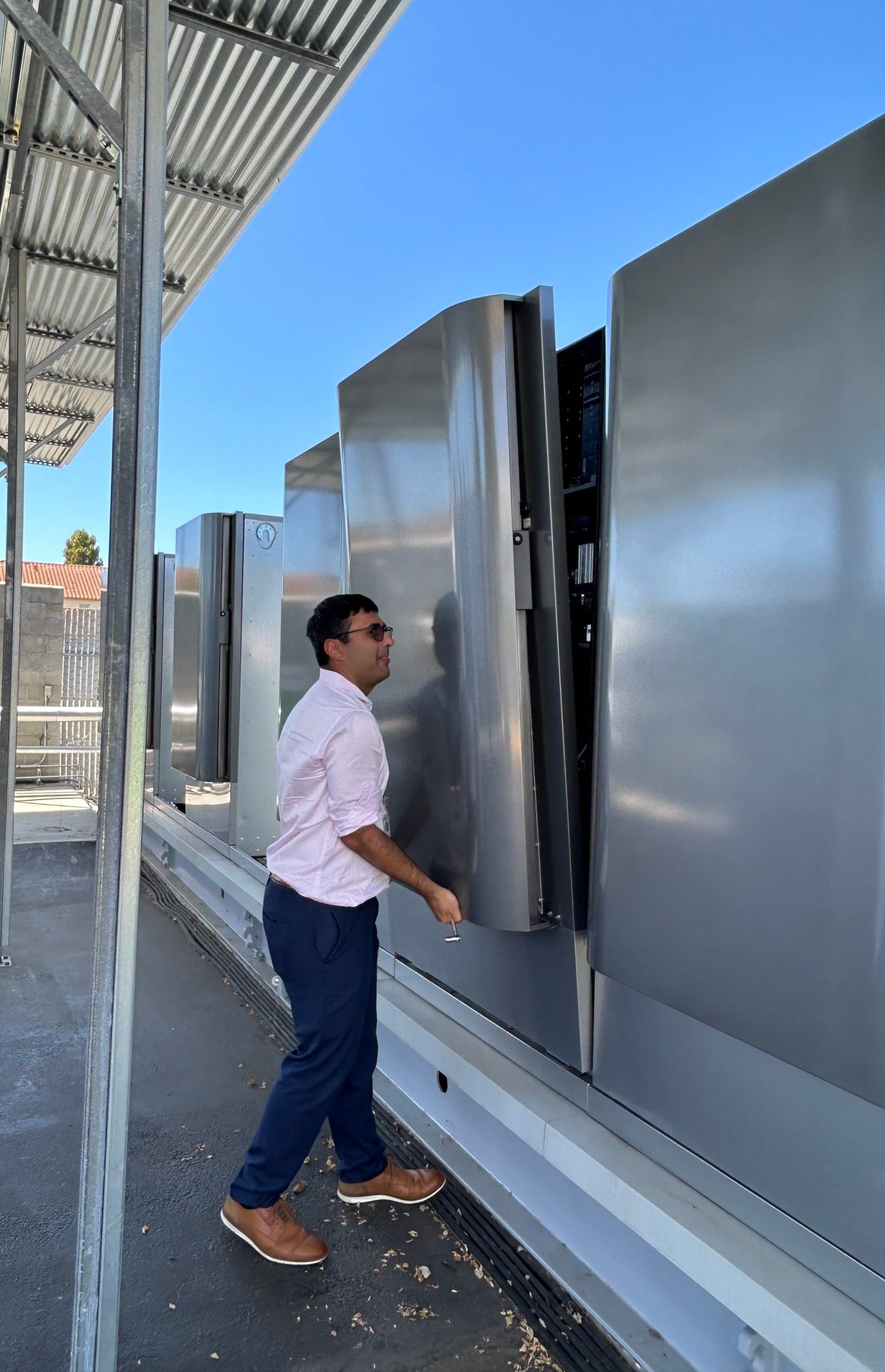 A Bloom Energy official lifts the door of an industrial fridge sized electrolyzer at the Ames National Laboratory in Mountain View, California.